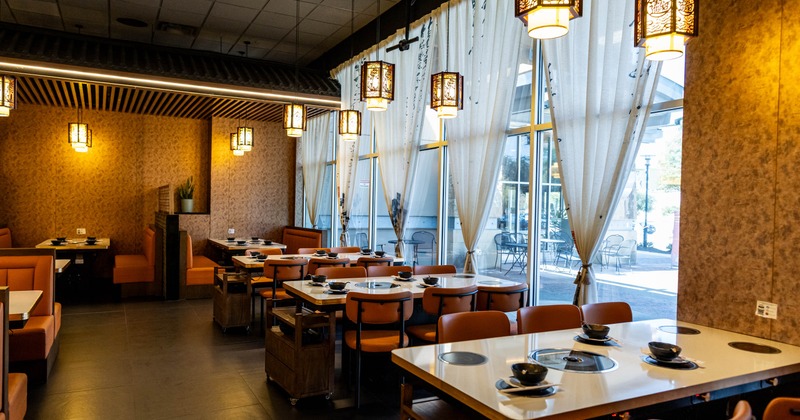 Interior with  warm orange booths and tables with hot pot burners