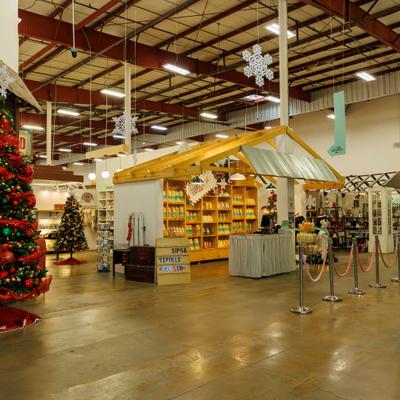 Indoor holiday market with Christmas trees, snowflake decorations, and wooden vendor booths.