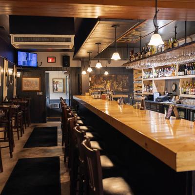 Interior with long wooden bar counter with several bar stools.