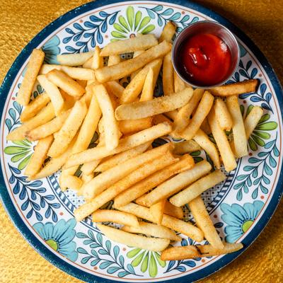 Fries served with a small cup of ketchup on a decorative floral ceramic plate.
