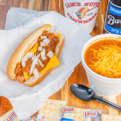 Chili dog with a cup of chili and crackers.