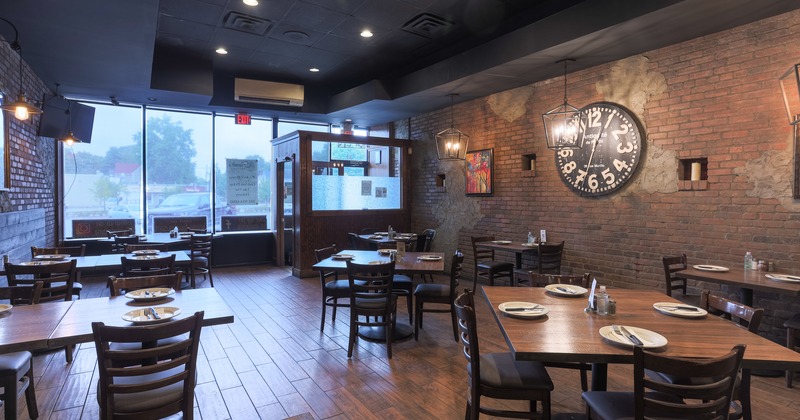 Interior, tables and seats, brick walls, table items, a large clock on a wall and a picture