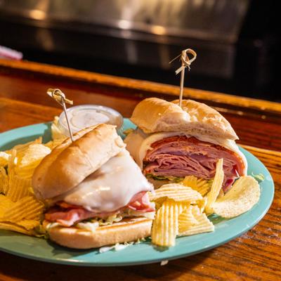 Italian Sub sandwich sliced in half and served with chips and a dipping sauce.