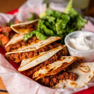 Ground beef quesadilla served with sour cream and greens.