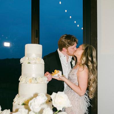 A couple kissing next to a wedding cake.