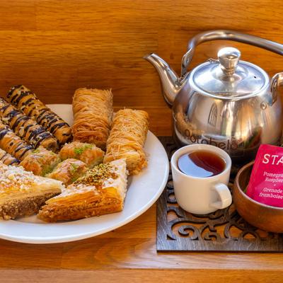 Dessert plate accompanied with a tea pot, tea bags and a cup of tea.
