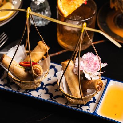 Two small baskets of spring rolls, accompanied by a cocktail.