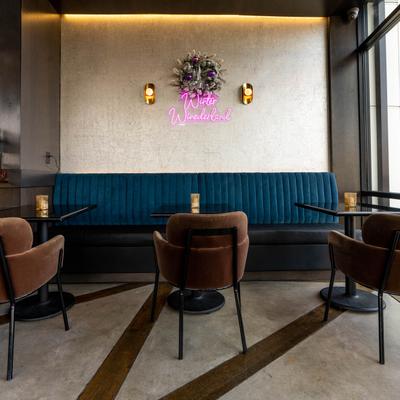 Interior, frontal view of banquette seating with tables by a window