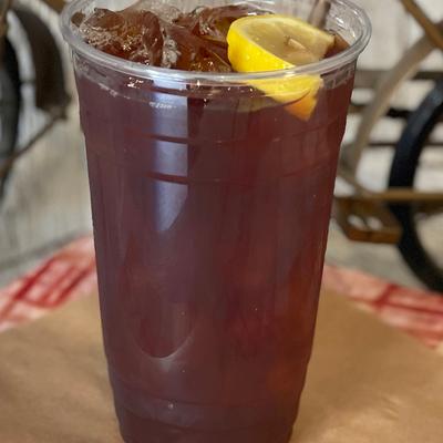 Iced drink served in a plastic cup with a slice of lemon.
