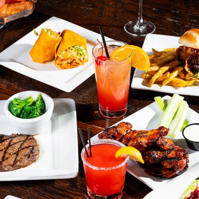 Assorted food plates and cocktail drinks displayed on table.