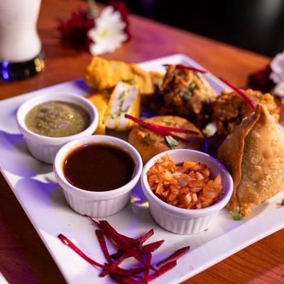 Assorted Indian appetizers with sauces on a plate.
