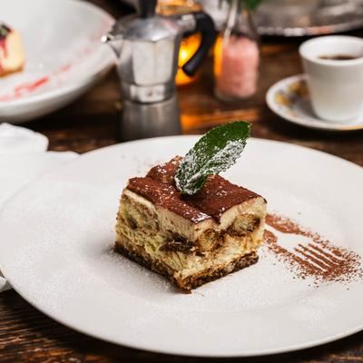 A slice of tiramisu topped with s mint leaf.