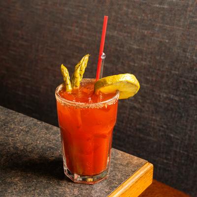 Bloody Mary cocktail garnished with asparagus and lime wheel.
