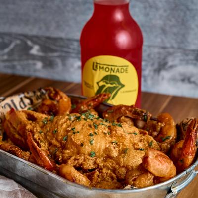 Lobster tail and shrimp covered in sauce and garnished with herbs.
