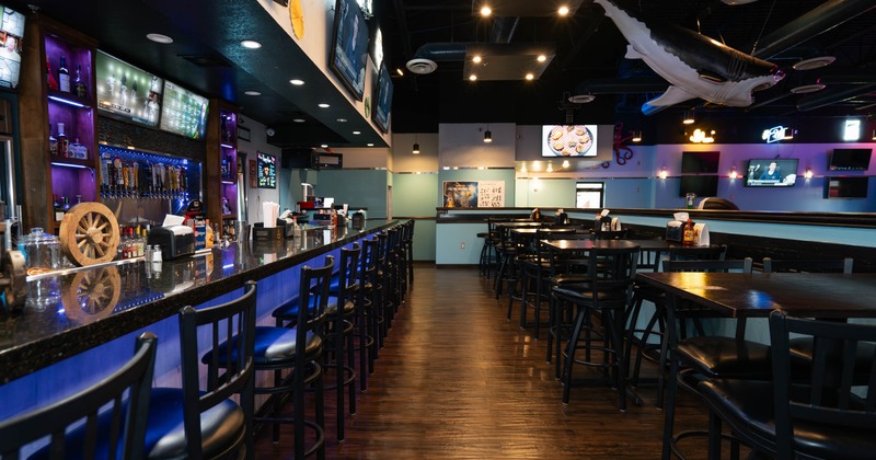 Interior with bar area with a counte and seating atea with arge shark hanging from the ceiling
