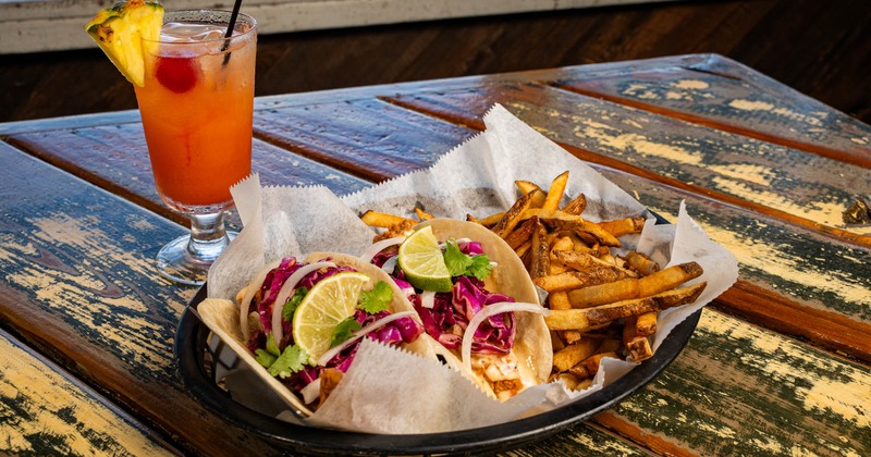 Fried fish tacos and fries paired with Mai Tai cocktail