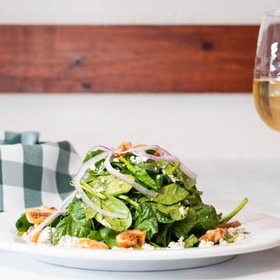 Baby spinach salad with figs, gorgonzola, walnuts, and onions, served with white wine.