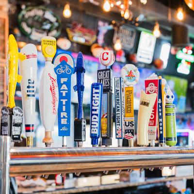 A row of diverse, colorful beer taps on a bar counter.