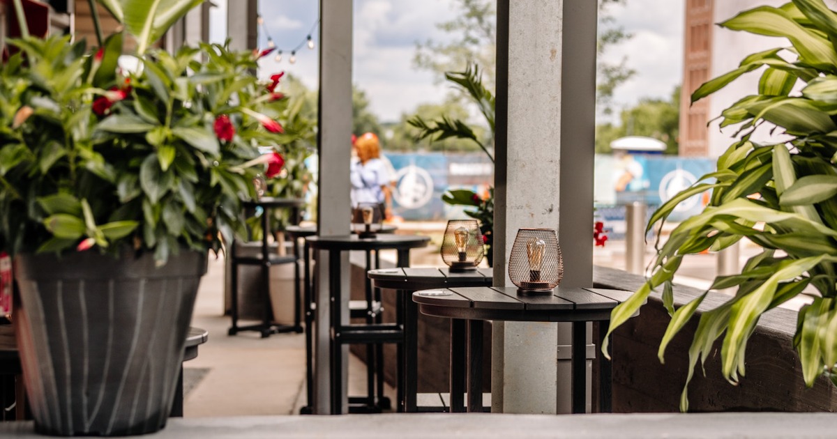High tables with lanterns, bar stools, and potted plants
