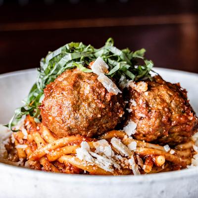 Meatballs over pasta with tomato sauce, parmesan and basil.