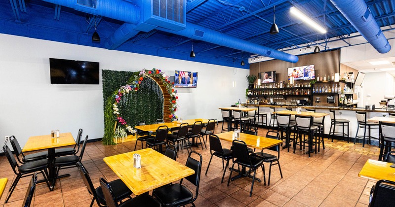 Interior, dining area, high and regular wooden top tables, bar with stools in the back