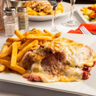 Cheese-covered corned beef sandwich served alongside fries