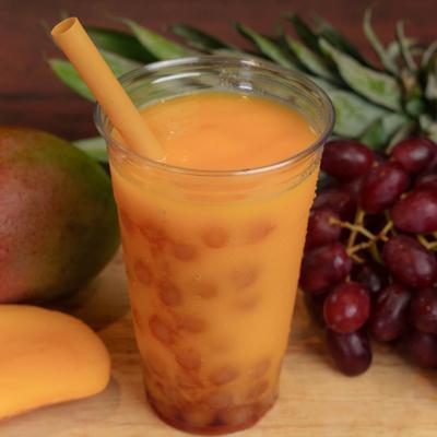 Mango Peach Boba cup on a table garnished with fresh fruits.