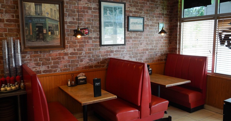 Cozy restaurant interior with red leather booths, wooden tables, and framed pictures on brick walls