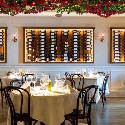 Fully set dining tables, wine racks on the wall.