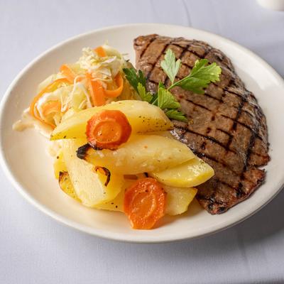 Grilled veal served with house potatoes and cabbage salad.