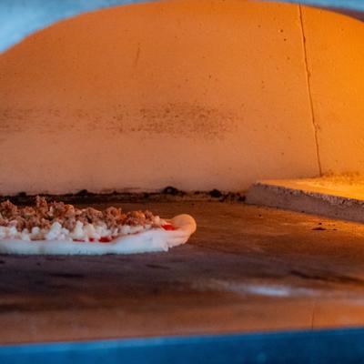 Pizza being baked inside a traditional wood-fired brick oven.