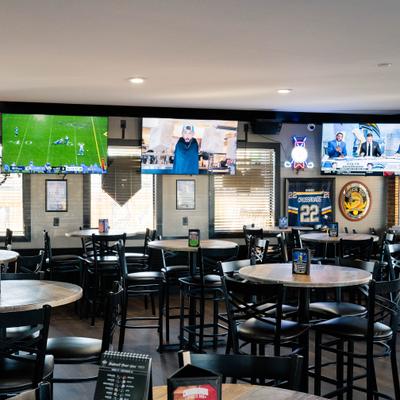 Interior with high tables, chairs and multiple TV screens.