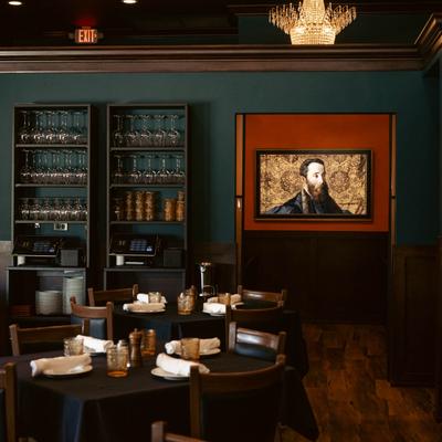 Seating room with set tables, glassware on the shelves, and wall art.