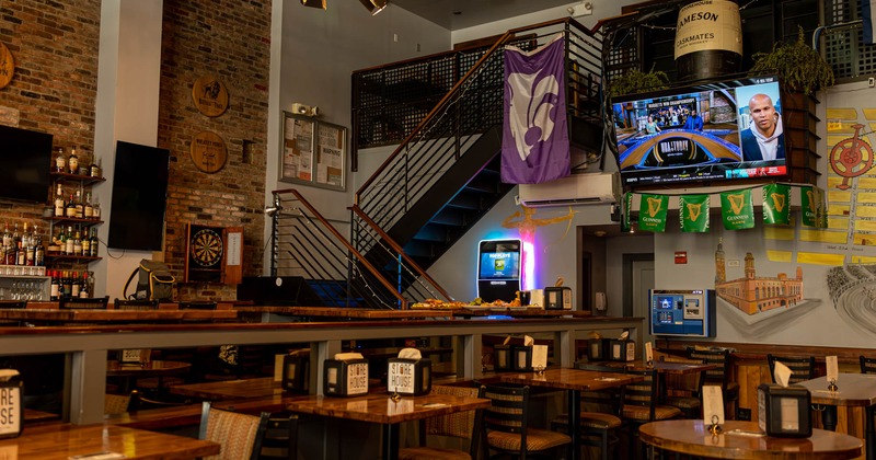 Seating area, large TV screen on the wall, and tables upstairs