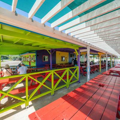 A colorful pergola space, with picnic tables and benches.