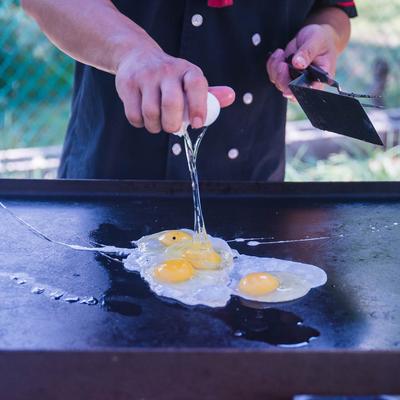 Chef cracking eggs onto a griddle.