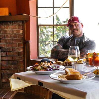 The owner posing by a table filled with food.