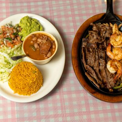 Mixed fajitas served with rice, charro beans, pico de gallo, lettuce salad, and guacamole.