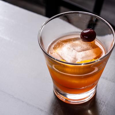 Aged Old Fashioned with orange peel and cherry garnish.