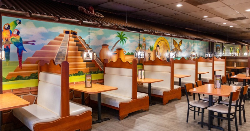 Interior, dining area, colorful Mayan motif mural on the wall, seating booths with tables