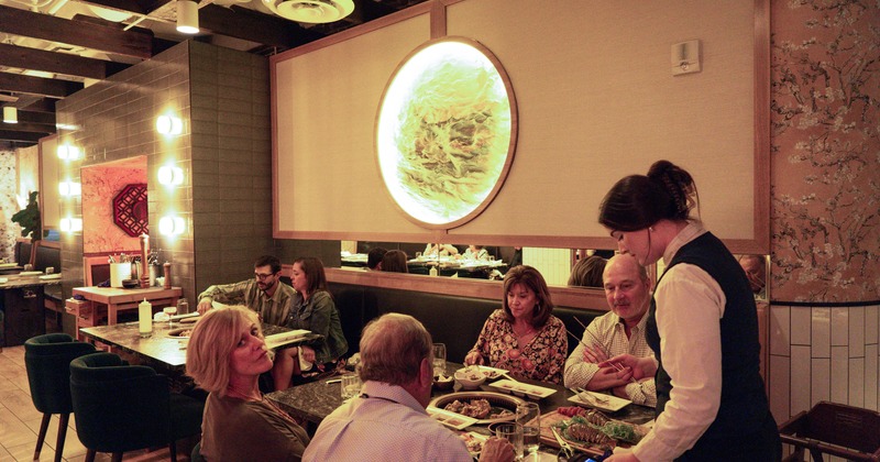 Interior, counter, chairs, drink bottles on shelves, decorative lighting, bartender
