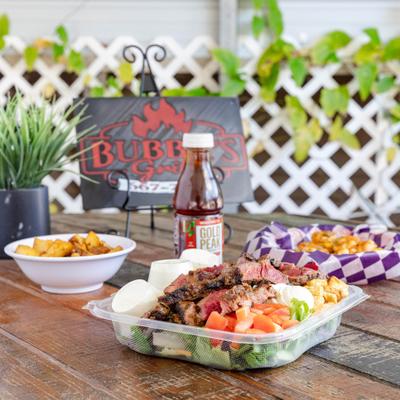 Grilled Steak Salad served on the table with two appetizers and a drink.