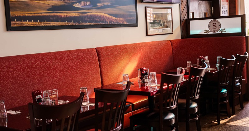 Interior, long banquette bench tables and chairs, near wall with framed pictures