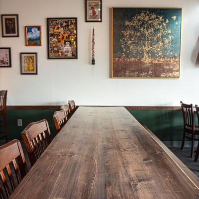 Interior with a long wooden dining table and framed art on the wall.