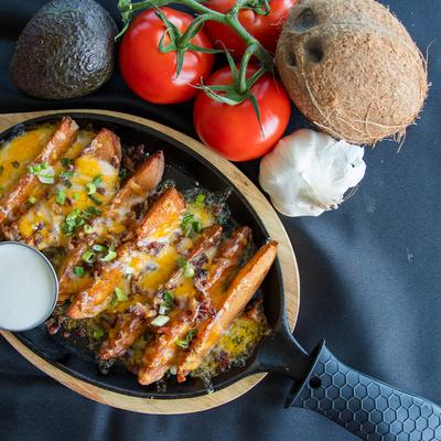 Loaded Fries Skillet served with a dipping sauce, served alongside fresh fruit and vegetables.