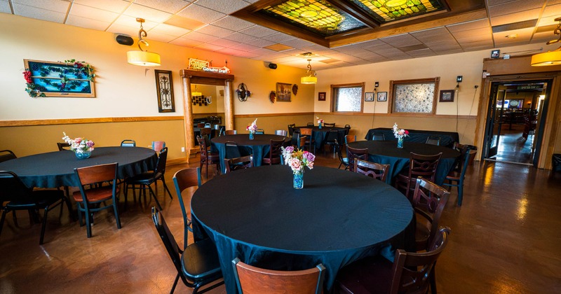 Dining room with black tablecloth tables beneath stained glass lights