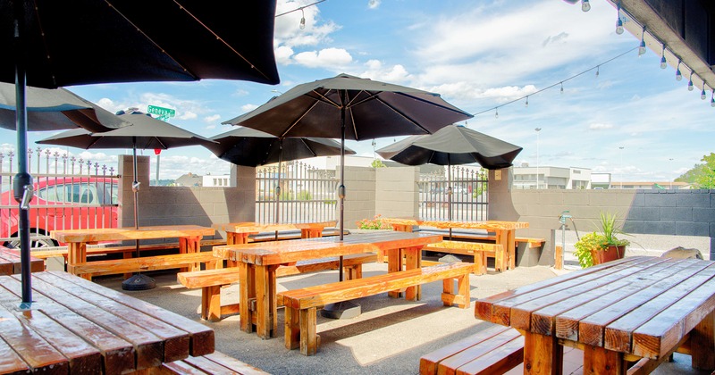 Outdoor seating area, wooden tables with benches, black parasols