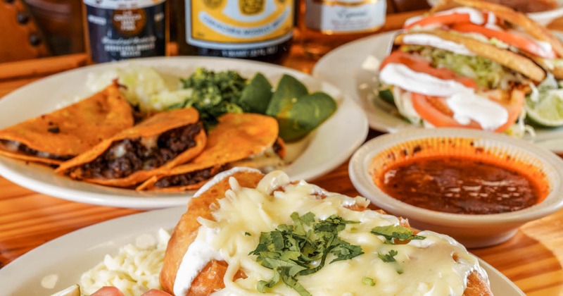Mexican plates with birria tacos, chimichanga, and salsa