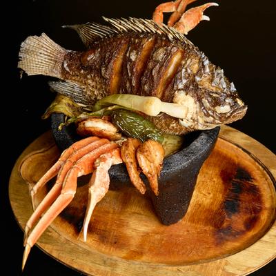 Seafood Molcajete, with grilled fish, crab legs, shrimp, scallops, onions, and peppers.