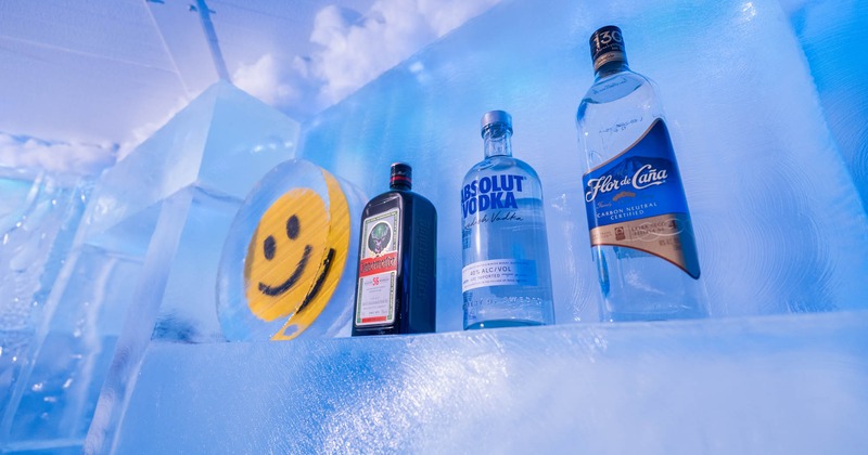 Liquor bottles rest on an ice shelf, alongside a smiley face plate